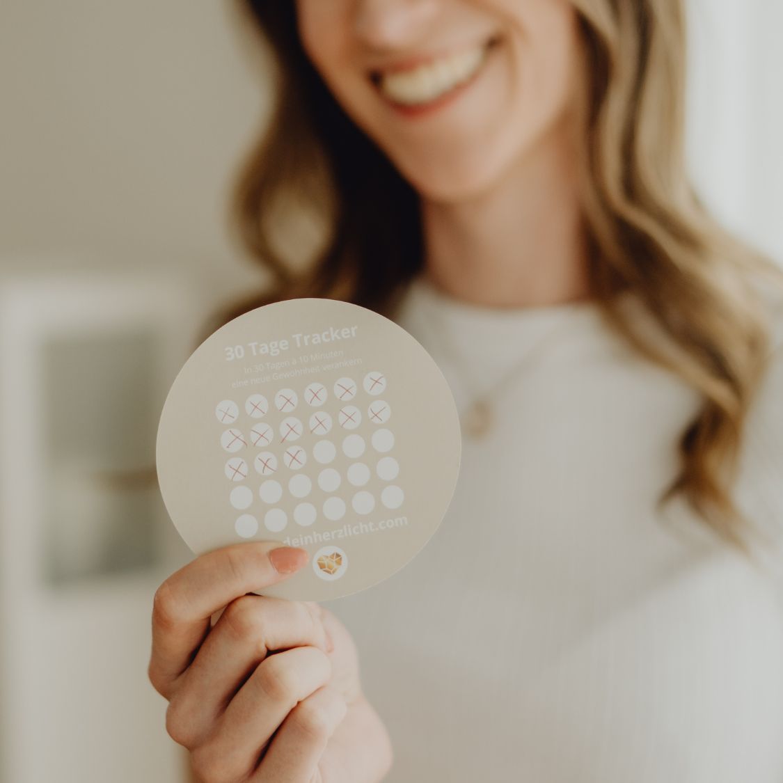 Eine Frau hält den 30 Tage Tracker in der Hand, der jedem HerzLicht beiliegt.
